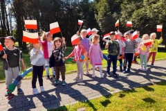 Grupa dzieci maszeruje z flagami Polski.