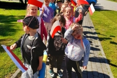  Grupa dzieci idzie w parach  w ręku trzymają flagi.