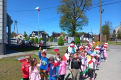 Grupa dzieci idzie w parach  w ręku trzymają flagi.