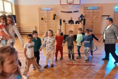 Dzieci trzymaja sie za ręce tworząc półkole. W tle widać drabinki drewniane.