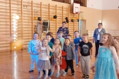 Grupa dzieci stoi w rozsypce. Za nimi stoją dwie panie.