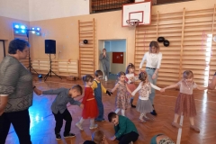 Dzieci trzymają się za ręce tworząc półkole. W tle widać drabinki drewniane.