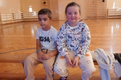 chłopiec i dziewczynka siedzą obok siebie na ławeczce.