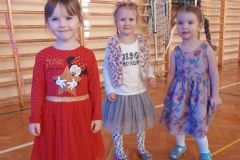 trzy dziewczynki ubrane w kolorowe sukienki stoją obok siebie.