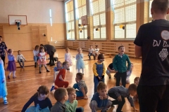 Grupa dzieci znajduje się na sali gimnastycznej.  Wszystkie dzieci są  w pozycji stojącej.