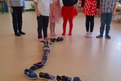 Kilkoro dzieci wróży sobie ustawiając buty w rzędzie.