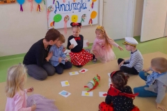 Dzieci siedzą w kole, na podłodze różne obrazki i butelka, dzieci kręcą butelką, wróżą sobie.