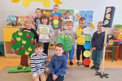 Grupa 8 chłopców stoi na podłodze. 3 trzyma sygnalizatory emocji, 5 drzewka emocji. 2 chłopców klęczy przed nimi na podłodze.