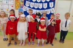 Dzieci stoją w dwóch rzędach przebrane za postacie z bajek. Za nimi napis dzień babci i dziadka na niebieskim tle.
