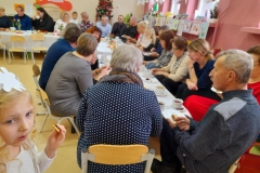 Babcie I dziadziowie siedzą wokół stołu.