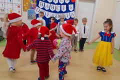 Dziewczynka przebrana,ekranach za królewnę Śnieżkę mówi wiersz, koło niej tańczą krasnoludki.