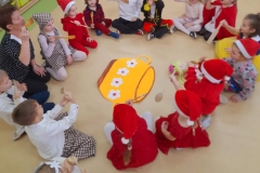 Dzieci siedzą na podłodze wokół garnka, udają że próbują zupę z drewnianych łyżek.