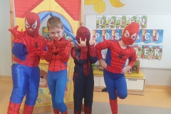 Sala przedszkolna. Czwórka dzieci w strojach Spider- Manów stoją przed teatrzykiem , za mimi tablica z napisem DZIEŃ POSTACI Z BAJEK.