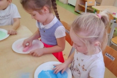 Dwie dziewczynki pocierają sól kolorową kredą.