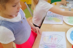 Dwie dziewczynki wypełniają motyla kolorową solą.