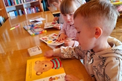 Trzech chłopców koloruje labirynt przy stoliku.