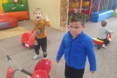 Chłopiec w niebieskiej bluzie stoi pośrodku sali, za nim stoi drugi. W tle kolorowe materace.