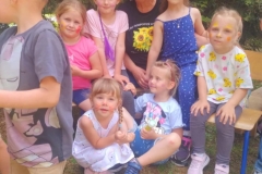 Kilkoro dziewczynek z wymalowanymi twarzami siedzi na kolanach u byłej pani sołtys.
