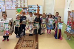 Kilkoro dzieci prezentuje się w kolorowych strojach wykonanych z różnych materiałów przeznaczonych do recyklingu.