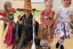 Trzy dziewczynki I chłopiec stoją w kolorowych strojach wykonanych z odpadów.