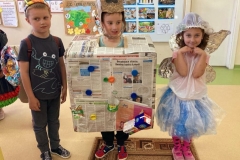 Kilkoro dzieci prezentuje się w kolorowych strojach wykonanych z różnych materiałów przeznaczonych do recyklingu.