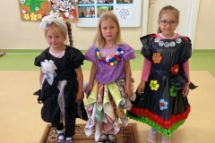 Trzy dziewczynki stoją w strojach wykonanych z materiałów przeznaczonych do recyklingu.