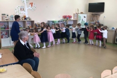 Przy piosence Zima,zima,zima wychowawczyni wprowadziła dzieci na salę. Dzieci idą jedno za drugim, trzymają się za ramiona tworzą pociąg. W tle widać jednego dziadzia.