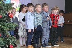 Dziesięcioro dzieci stoi w rzędzie, patrząc przed siebie. Ubrane są w kolorowe stroje.