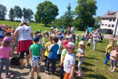 Dzieci w kolorowych strojach stoją w rozsypce na trawie.