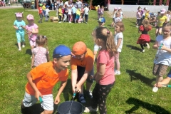 Dzieci w kolorowych strojach biegają po trawie.