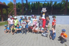 Zdjęcie przedstawia grupę dzieci stojących i kucających. Pośrodku nich jest myszka.