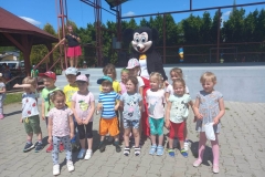 Grupa dzici stoi w dwóch rzędach. Pośród nich postać myszki.