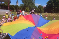 Dzieci trzymają w rękach kolorową, okrągłą chustę.