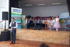 Zdjęcie przedstawia osobę dorosłą i grupę dzieci w kolorowych strojach.