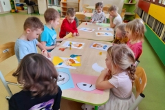 Kilkoro dzieci stoi w rzędzie, przed nimi siedzi czworo dzieci, każde z nich trzyma w ręku bużki  emocje.