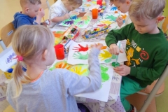 Kilkoro dzieci stoi w rzędzie, przed nimi siedzi czworo dzieci, każde z nich trzyma w ręku bużki  emocje.