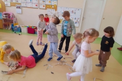 Grupa dzieci bawi się podarta gazetą w rytm muzyki.