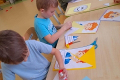 Trzech chłopców I dziewczynka siedzą przy stoliku, układają puzzle z kolorowych buziek, emocji.