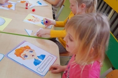 Trzy dziewczynki I chłopiec układają puzzle z kolorowych buziek, emocji.