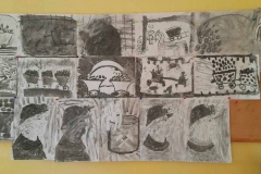 Na gazetce wiszą pracę dzieci wykonane czarnym węglem.