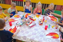 Przy stoliku siedzi grupa dzieci, malują farbami iskierki.