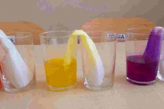 Na stole stoi 3 puste szklanki, w 3 jest zabarwiona wodą do której włożone są papierowe ręczniki.