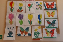 Na tablicy wiszą kolorowe prace dzieci.