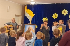 Dzieci ustawione plecami, pani gra na gitarze, dzieci powtarzają ruchy, które pokazują panie.