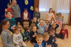 Dzieci przedszkolne siedzą na podłodze z dziećmi z ośrodka, jeden chłopiec jest na wózku inwalidzk, pani trzyma na kolanach dziewczynkę.