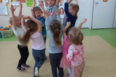 Dzieci stoją w grupie, ręce trzymają do góry, okazują radość.