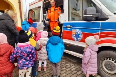 Ratownik stoi w karetce, dzieci witają się z nim