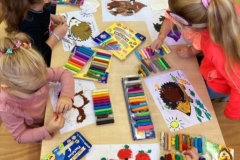 Sześć dziewczynek siedzi przy stole, wyklejają plasteliną kolorowe jeże, na stole leży kolorowa plastelina.