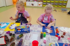 Chłopiec maluję palcami choinkę.