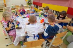 Piątka dzieci wykonuje prace z płatków kosmetycznych na niebieskich i czarnych kartkach.